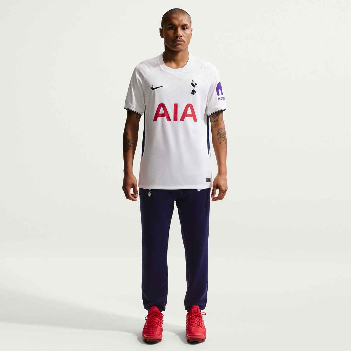 Person wearing a white sports jersey with red text and navy pants on a white background