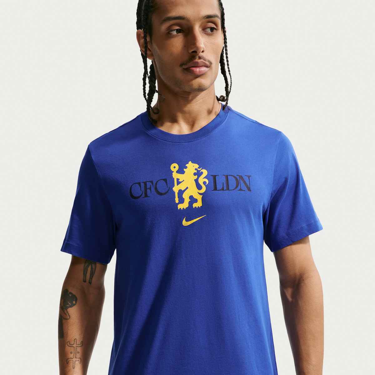 Man wearing a blue t-shirt with a logo and text on a plain background
