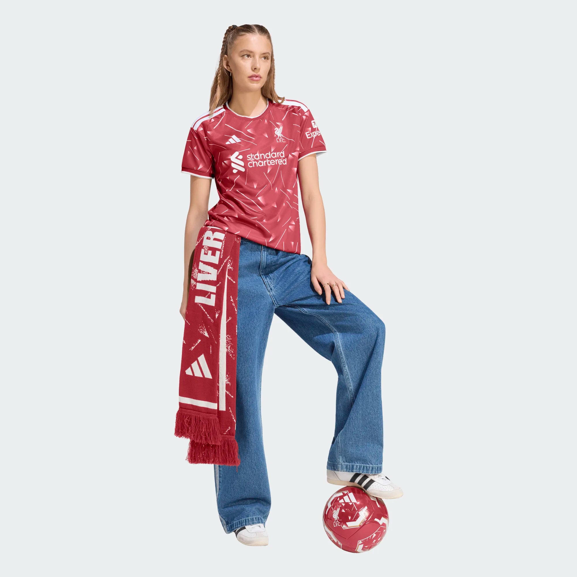 Person wearing a red sports jersey and scarf, standing with a soccer ball on a white background