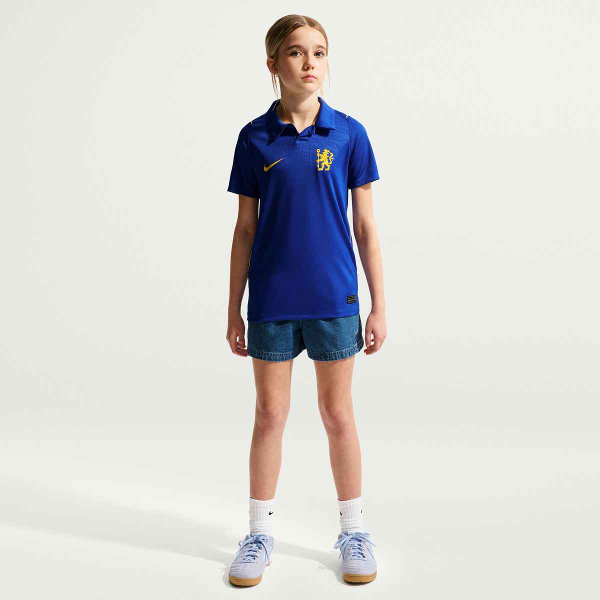 Young girl wearing a blue sports jersey with a logo on a white background