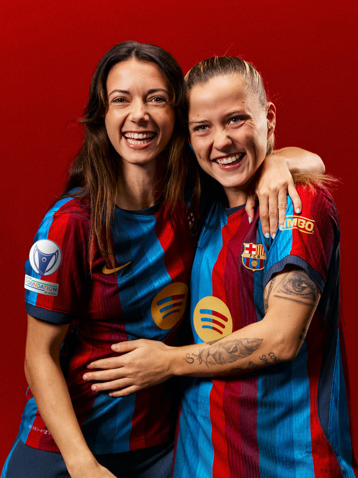 Two people wearing Barcelona football jerseys against a red background